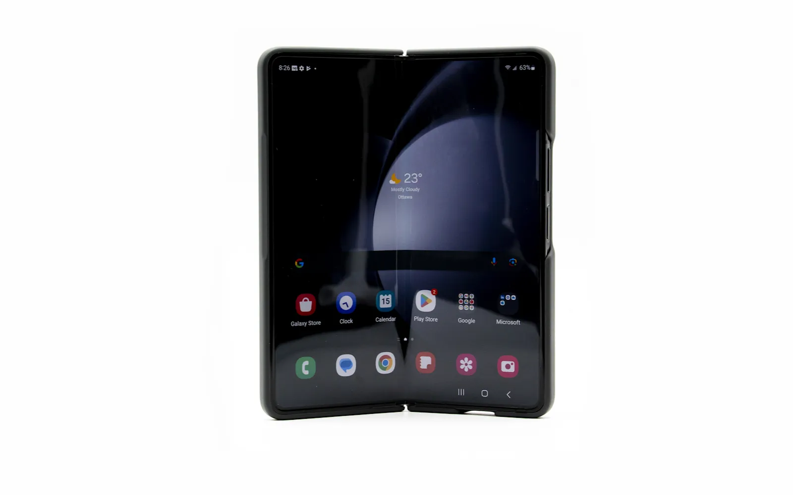 A Samsung Galaxy Z Fold standing open on a white surface, its inner screen showing the home screen