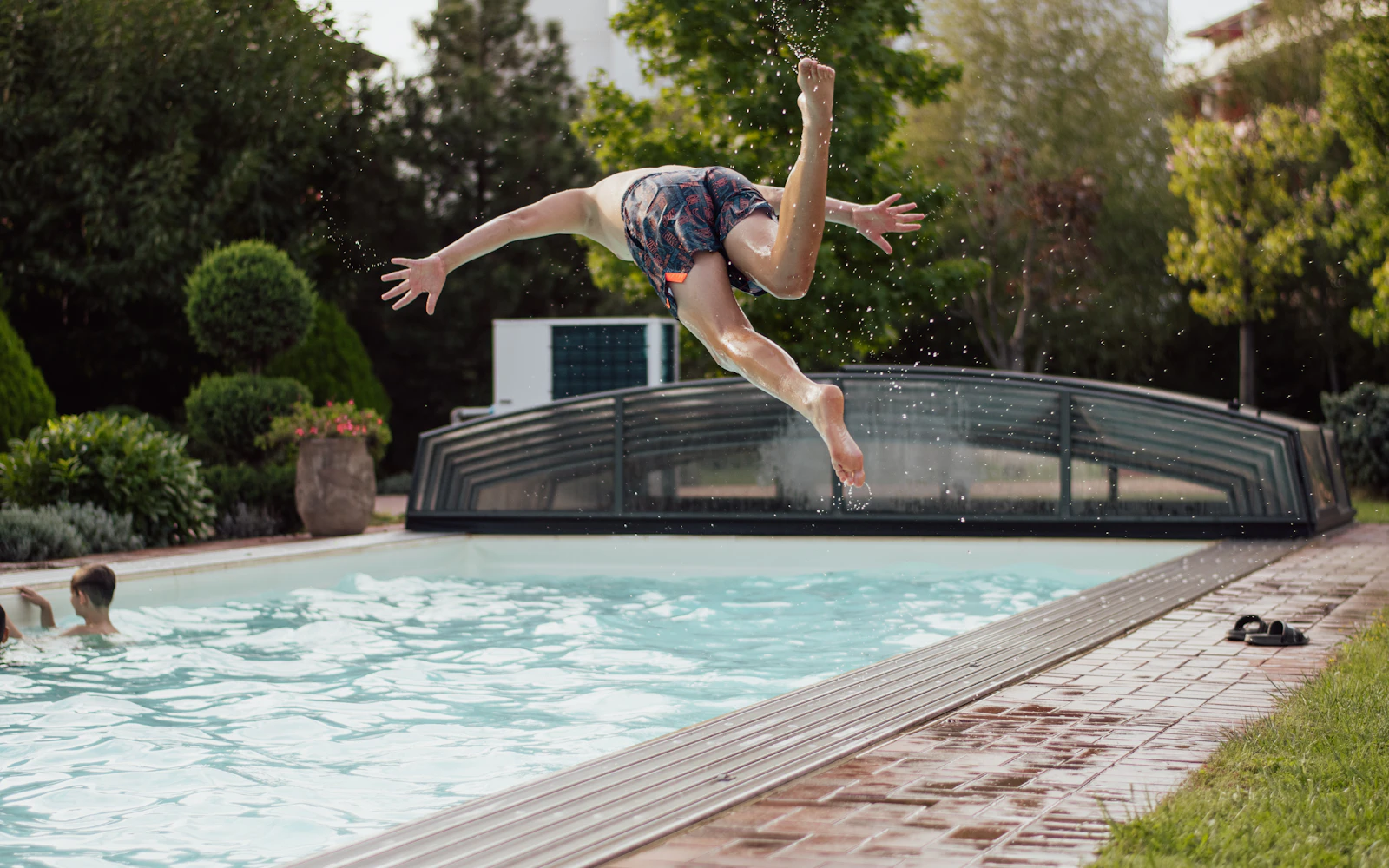 A man diving into a backyard swimming pool on a summer day