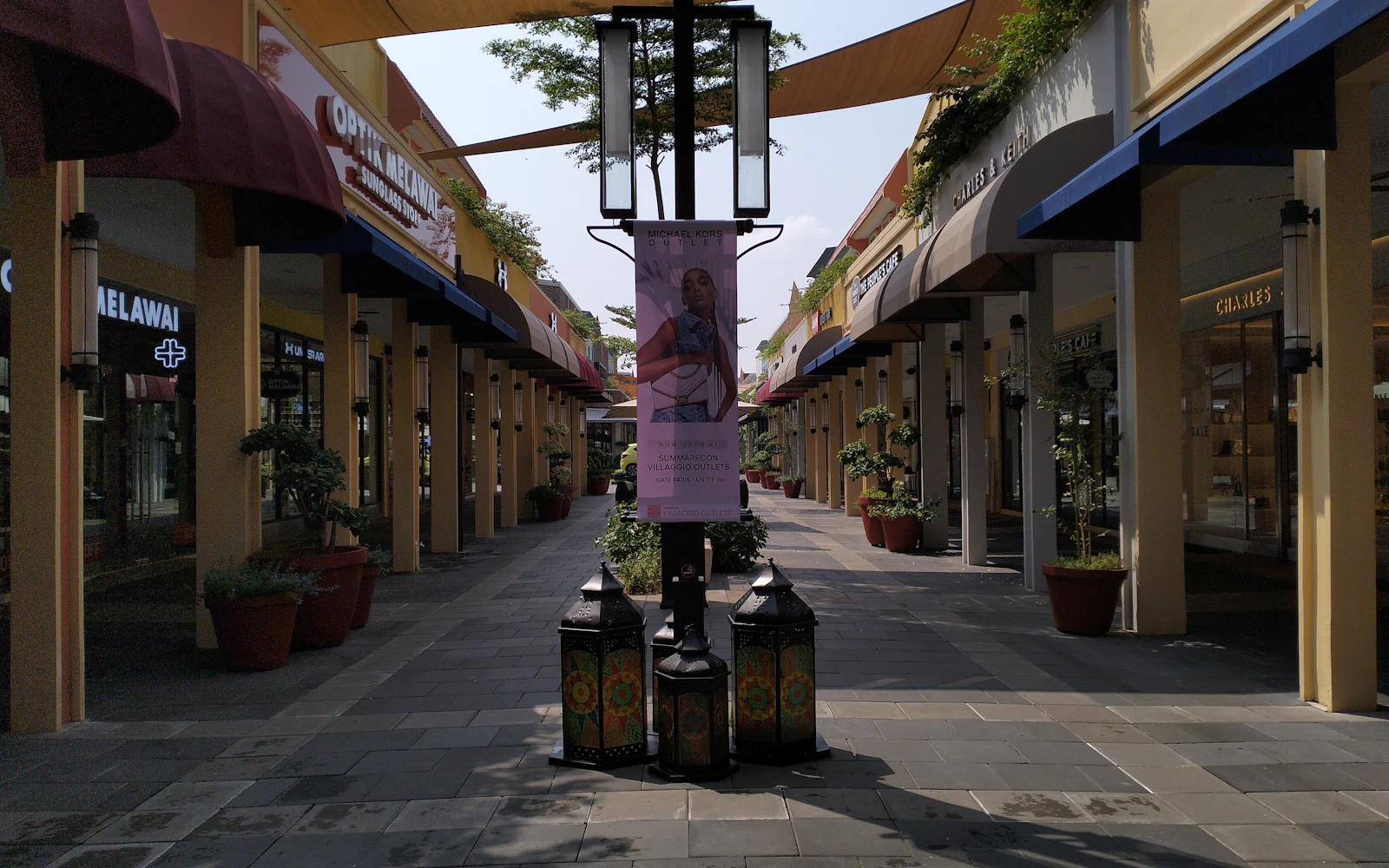 An open-air outlet center street lined with shops under covered walkways and awnings