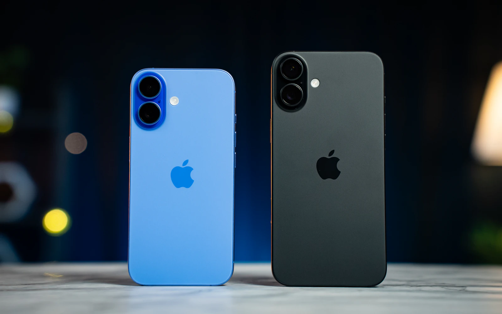 A blue iPhone and a black iPhone standing side by side, their rear cameras facing the viewer