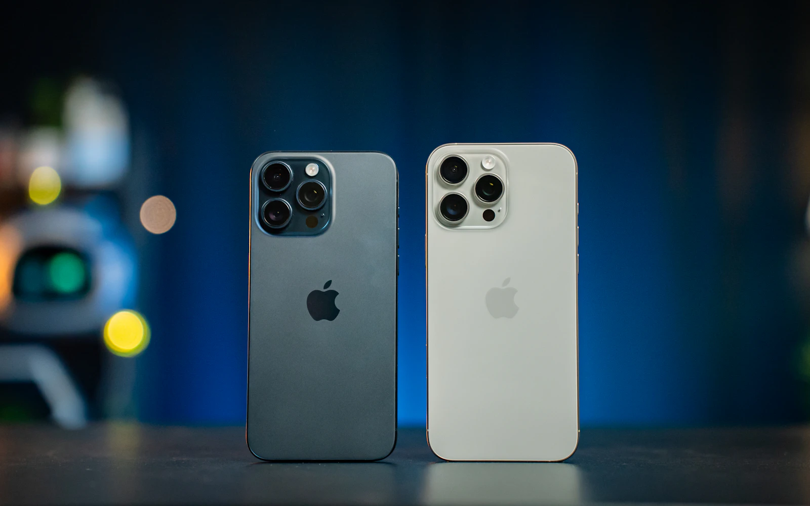 Two iPhone Pro models, one black and one natural titanium, standing side by side