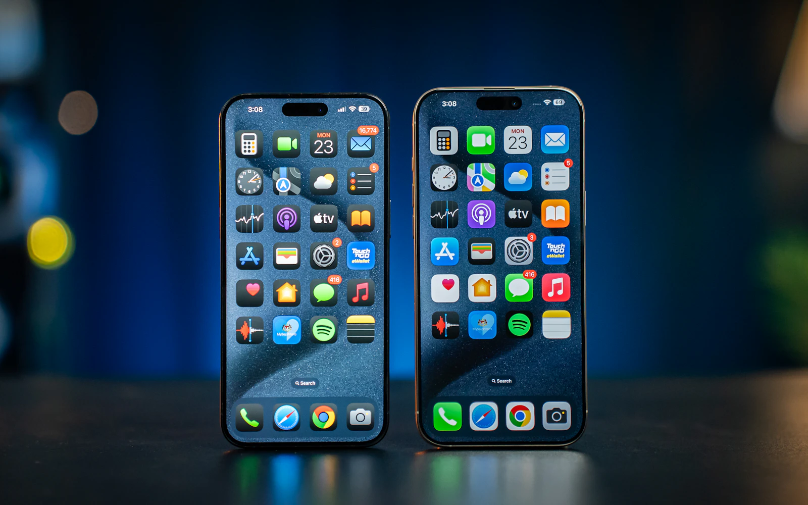 Two recent iPhones standing side by side on a table, both showing their home screens
