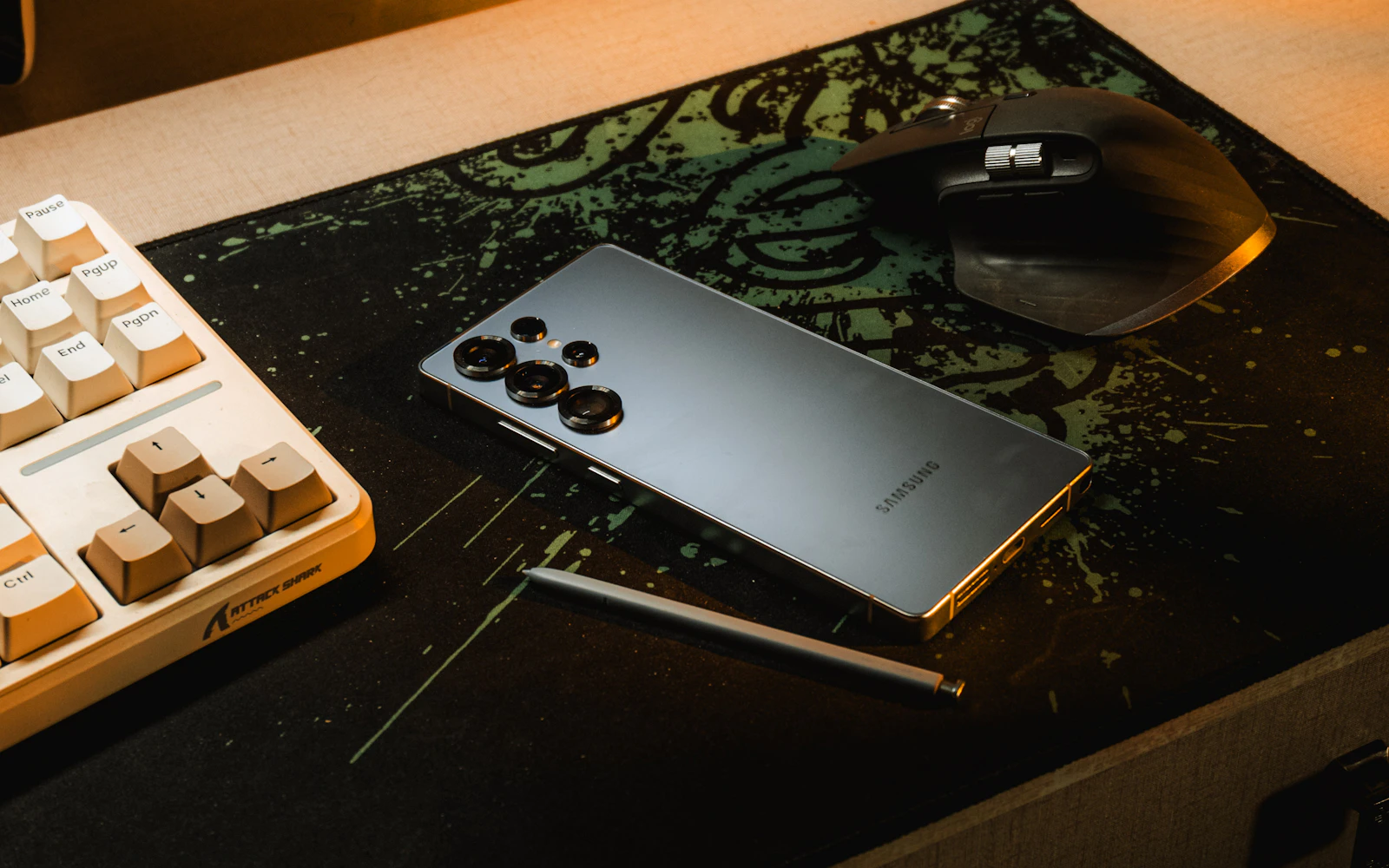 A Samsung Galaxy S Ultra lying on a desk mat beside a keyboard, a mouse and its S Pen